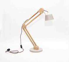 a wooden desk lamp with a white shade on the base and a cord attached to it