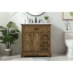 a bathroom with a toilet, sink and wooden cabinet next to a potted plant