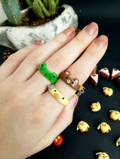 a woman's hand with two rings on it and some small toys in the background