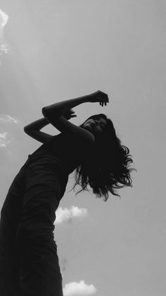 black and white photograph of a woman reaching up into the sky