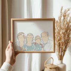 a person holding up a framed photo with the image of two men and one woman