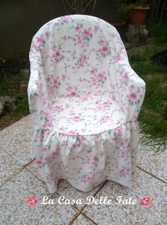 a white chair with pink flowers on it sitting in the middle of a patio area