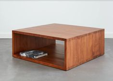 a wooden coffee table with a book on the bottom and a magazine rack underneath it