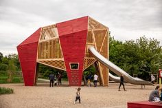 children are playing in the sand near a large wooden structure with a slide on it