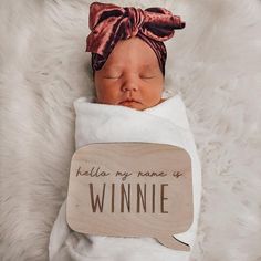 a newborn baby wrapped in a white blanket with a wooden sign that says hello my name is winnie