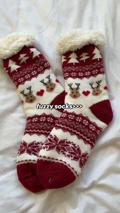 a pair of red and white socks with reindeers on them, laying on a bed