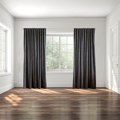 an empty room with wood floors and black curtains