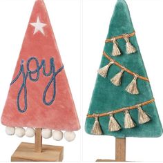 two small christmas trees with tassels on them and the word joy written in blue