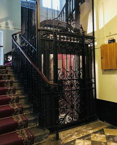 an ornate iron gate in the middle of a staircase leading up to a second story