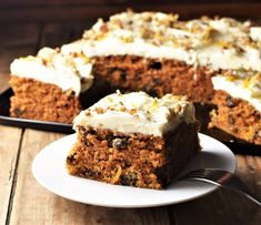 a piece of carrot cake on a white plate with a fork next to the slice