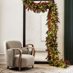 a chair sitting in front of a mirror covered in christmas lights and a holiday garland