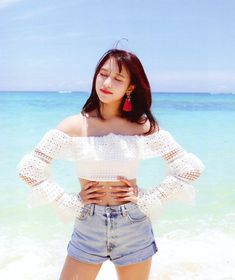 a woman standing on the beach with her hands on her hips and looking off to the side