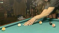 a woman leaning over a pool table with balls on it