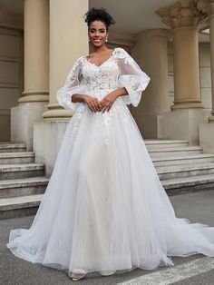 a woman standing in front of some steps wearing a white wedding dress with sheer sleeves