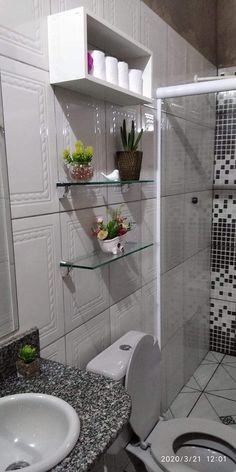 a white toilet sitting next to a sink under a bathroom mirror with shelves above it