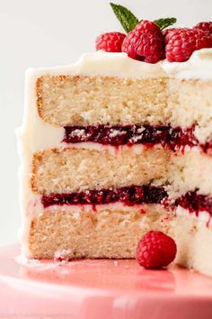 a close up of a slice of cake with raspberries on top and white frosting