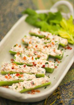 celery sticks with cream cheese and garnishes on a white platter