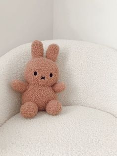 a small stuffed animal sitting on top of a white couch next to a wall and window