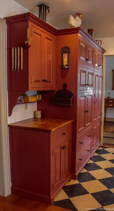 a kitchen with red cabinets and black and white checkered flooring on the walls