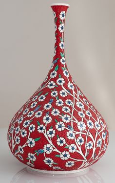 a red vase with white and blue flowers on it