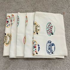 four white napkins with designs on them sitting on the floor next to each other