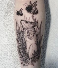 a tattoo on the leg of a person with flowers and bees flying around it's legs