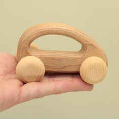 a hand holding a wooden toy car in it's palm