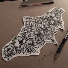 a piece of paper with flowers and leaves on it next to a pen, scissors and ink