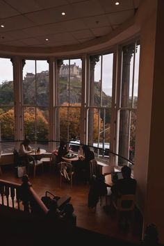 two people sitting at tables in front of large windows looking out onto the hills outside