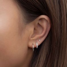 a woman wearing an earring with two small diamonds on the top of her ear