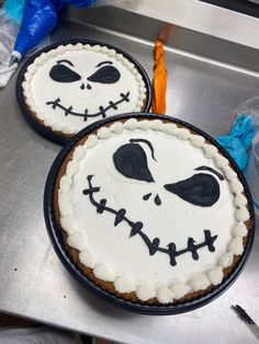 two decorated cakes sitting on top of a metal counter next to plastic bags and forks