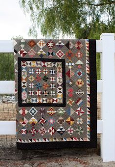 a quilt hanging on the side of a white fence