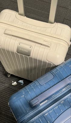 two pieces of luggage sitting on the floor next to each other, one blue and one white