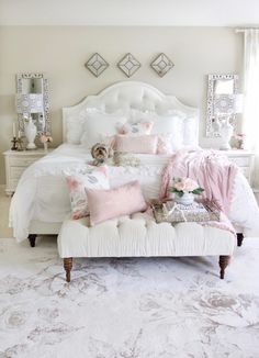 a white bed with pillows and blankets on top of it in a room filled with mirrors