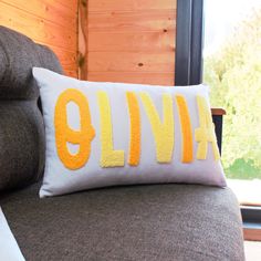 a pillow with the word glimf on it sitting on a couch in front of a window