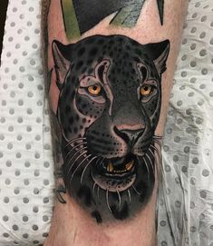 a man's leg with a black and grey tattoo of a cheetah