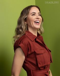 a woman in a red dress smiling and looking to the side with her right hand on her hip