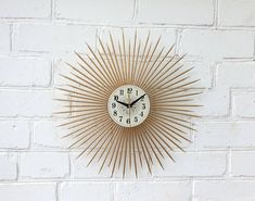 a white brick wall with a gold clock on it and the time is 11 00