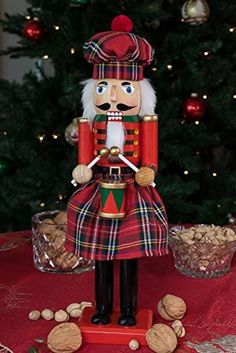 a nutcracker figurine sitting on top of a table next to a christmas tree