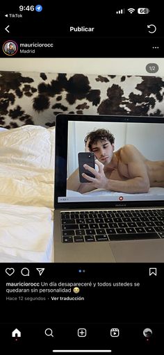 an open laptop computer sitting on top of a bed next to a cow print pillow