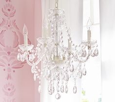 a chandelier hanging from the side of a window next to a pink wall