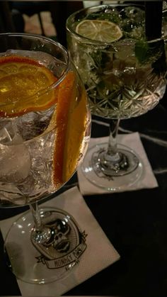 two glasses filled with drinks sitting on top of a table