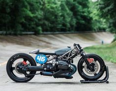 a black motorcycle parked on the side of a road next to a lush green forest