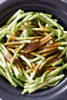 a bowl filled with green beans covered in sauce