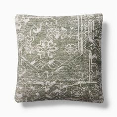 a green and white pillow with an intricate design on the front, sitting against a white wall