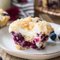 a blueberry muffin on a white plate with berries