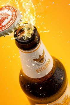 an open beer bottle with water splashing out of it's top and bottom