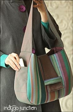 a woman is holding a multicolored purse