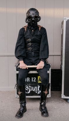 a man sitting on top of a chair wearing a gas mask