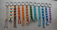 several different colored braided key chains are lined up on a gray surface, with one in the middle